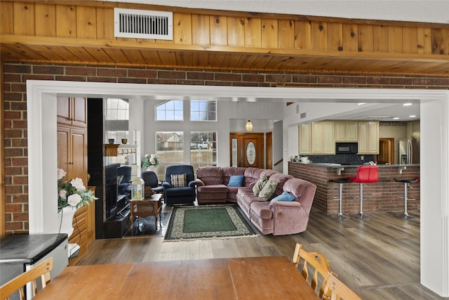 living room featuring brick wall and dark hardwood / wood-style floors