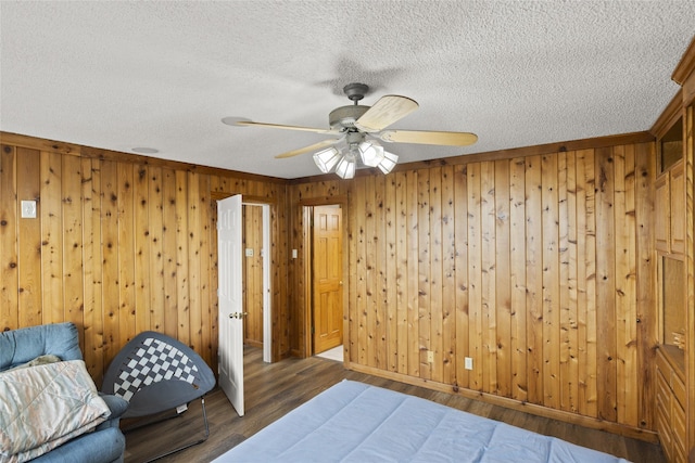 unfurnished bedroom featuring wooden walls, ceiling fan, dark hardwood / wood-style flooring, and a textured ceiling