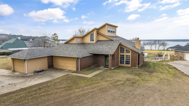 view of front of home featuring a garage, a front lawn, and a water view