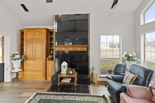 living room featuring ceiling fan, a textured ceiling, and light hardwood / wood-style floors