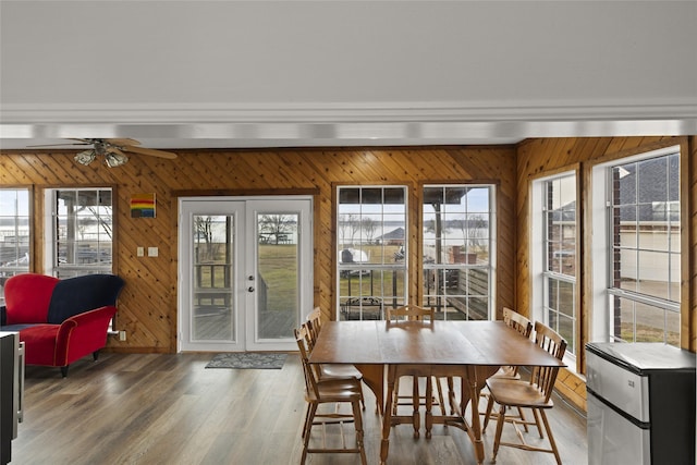 dining area featuring hardwood / wood-style flooring, wooden walls, and french doors