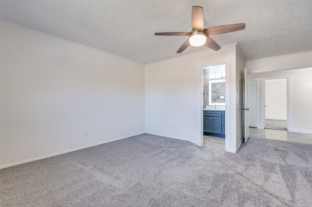 unfurnished bedroom with ensuite bathroom, light colored carpet, ceiling fan, and a textured ceiling