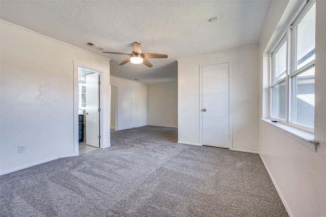 spare room with crown molding, ceiling fan, light carpet, and a textured ceiling