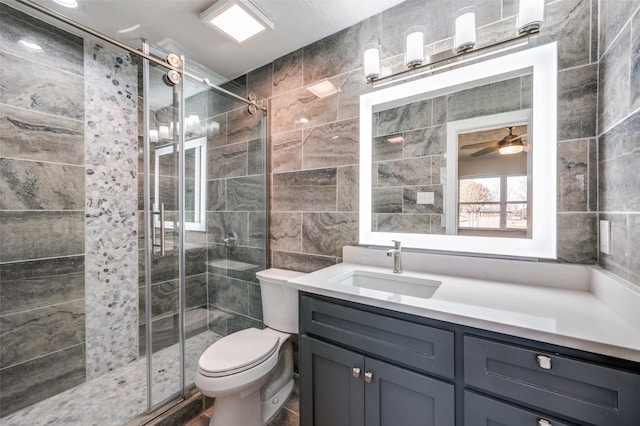 bathroom featuring tile walls, vanity, an enclosed shower, ceiling fan, and toilet