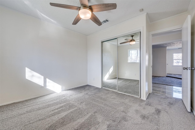 unfurnished bedroom featuring ceiling fan, light colored carpet, a closet, and a textured ceiling