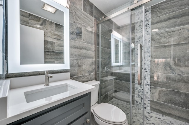 bathroom featuring vanity, toilet, a shower with door, and tile walls