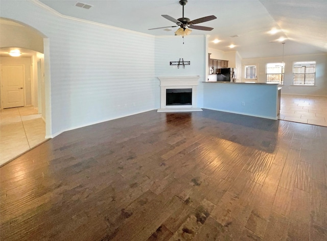 unfurnished living room with vaulted ceiling, ornamental molding, wood-type flooring, and ceiling fan