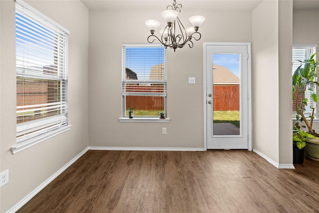 unfurnished dining area featuring wood-type flooring and a notable chandelier