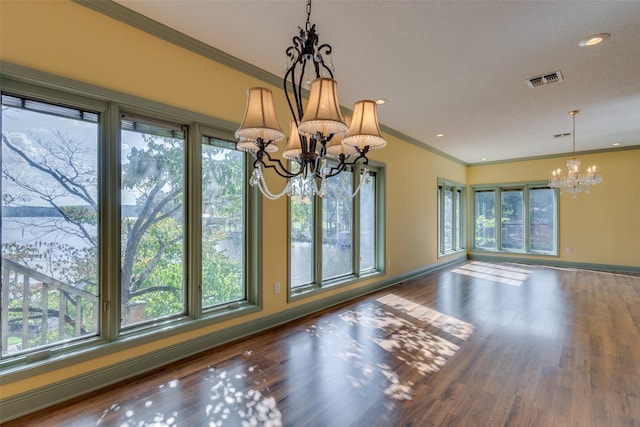 unfurnished dining area with a notable chandelier, ornamental molding, hardwood / wood-style floors, and a healthy amount of sunlight