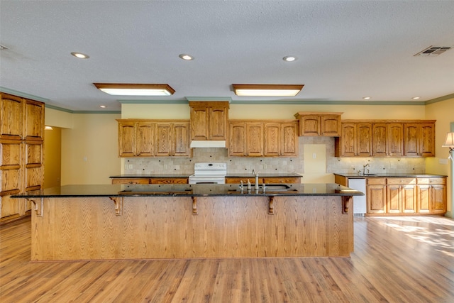 kitchen with a kitchen bar, sink, ornamental molding, white appliances, and a large island