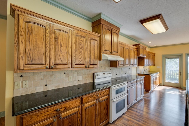 kitchen featuring sink, crown molding, light hardwood / wood-style flooring, dark stone countertops, and range with two ovens