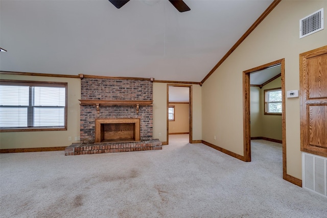 unfurnished living room with lofted ceiling, crown molding, a brick fireplace, ceiling fan, and light colored carpet