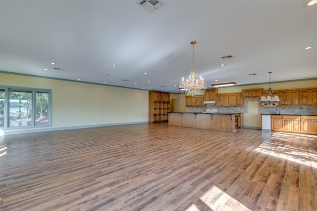 unfurnished living room featuring crown molding, light hardwood / wood-style floors, and a chandelier