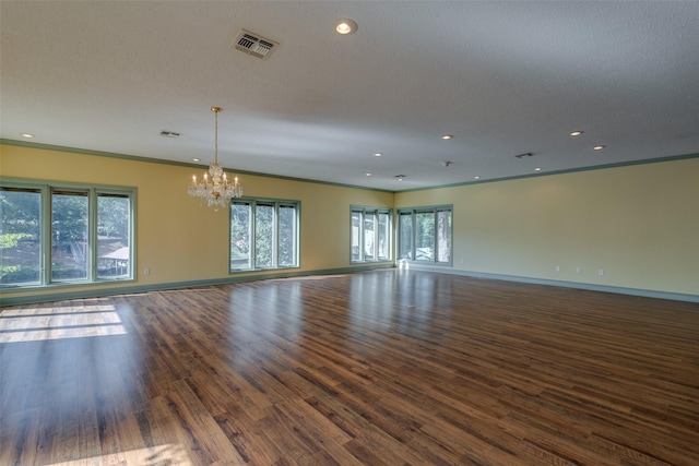 empty room with crown molding, dark wood-type flooring, a textured ceiling, and a chandelier