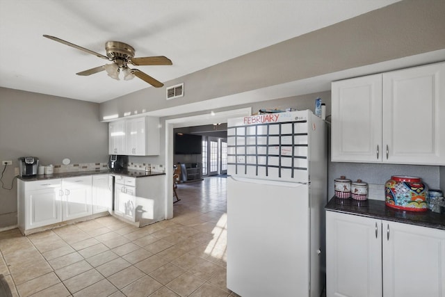 kitchen with visible vents, freestanding refrigerator, dark countertops, and white cabinetry