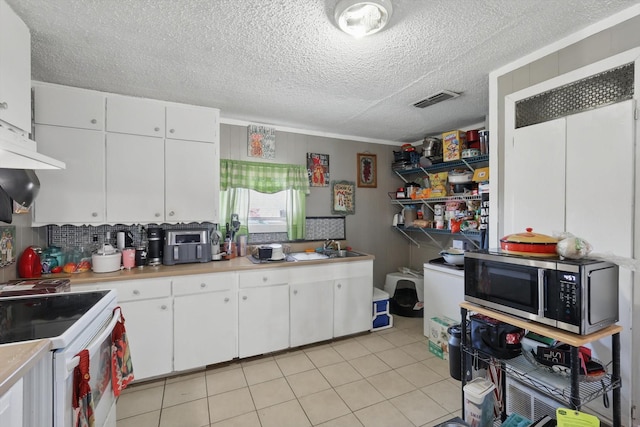 kitchen featuring white cabinetry, visible vents, stainless steel microwave, and light countertops