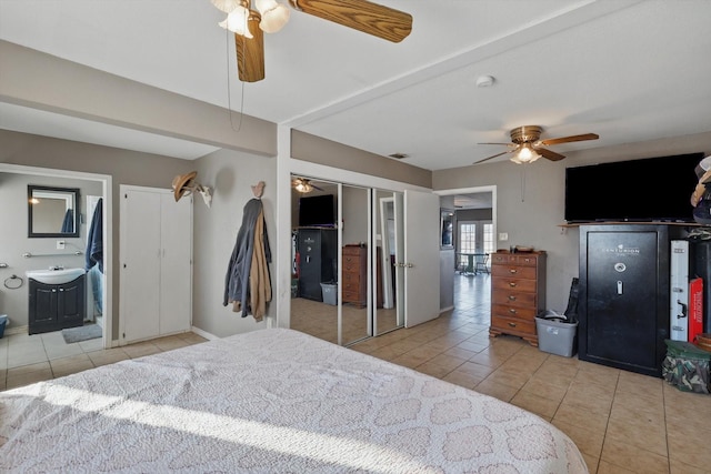 bedroom featuring a ceiling fan, light tile patterned flooring, visible vents, and ensuite bath