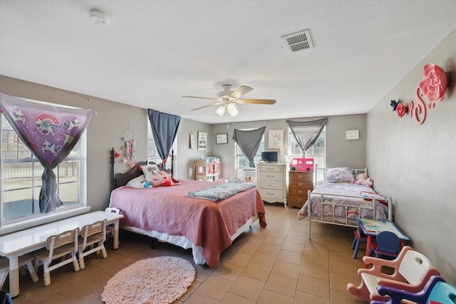 bedroom with ceiling fan, visible vents, a textured ceiling, and tile patterned floors