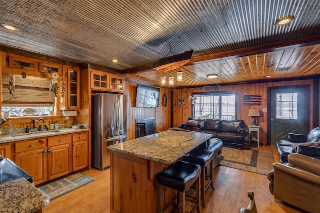 kitchen with stainless steel refrigerator, light hardwood / wood-style floors, sink, and a kitchen island