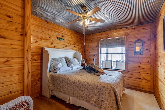 bedroom with wooden walls, ceiling fan, and light wood-type flooring