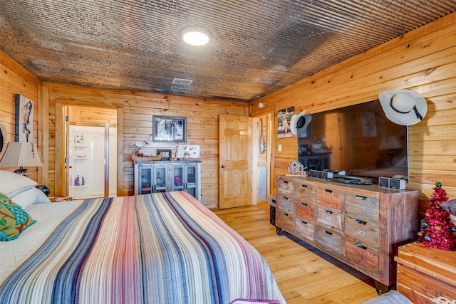 bedroom with light wood-type flooring and wood walls