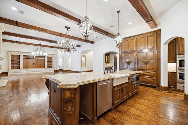 kitchen with dark wood-type flooring, sink, decorative light fixtures, stainless steel appliances, and a large island