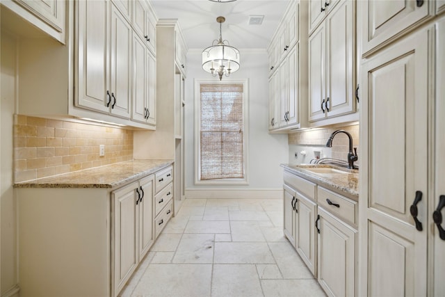 kitchen featuring light stone counters, sink, decorative light fixtures, and ornamental molding