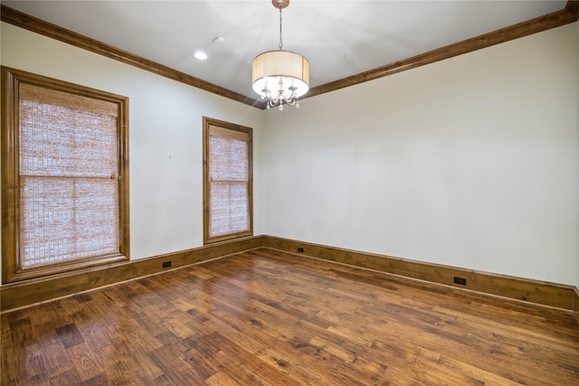 spare room featuring dark wood-type flooring, ornamental molding, and a chandelier