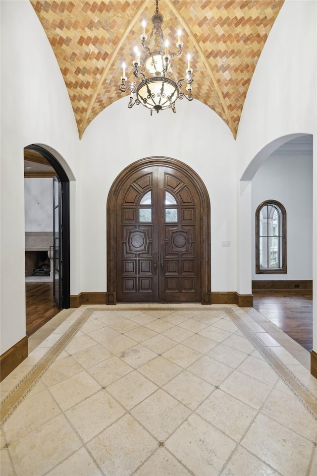 entryway with brick ceiling, a chandelier, and high vaulted ceiling