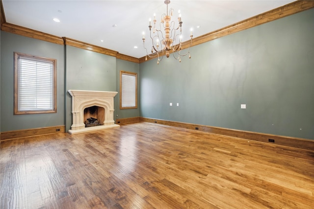 unfurnished living room with a notable chandelier, ornamental molding, and light hardwood / wood-style floors