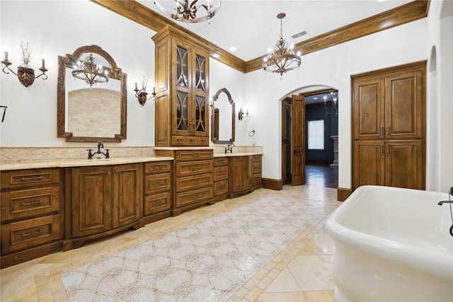 bathroom with an inviting chandelier, ornamental molding, a tub to relax in, and vanity