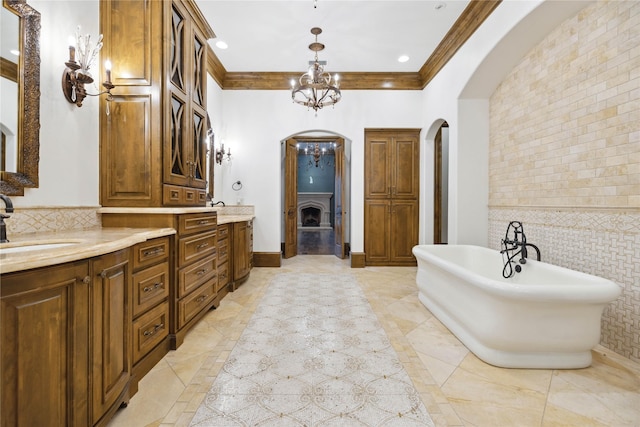 bathroom with an inviting chandelier, ornamental molding, vanity, a bathing tub, and backsplash