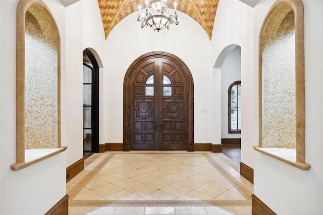 foyer entrance with brick ceiling, high vaulted ceiling, and a notable chandelier