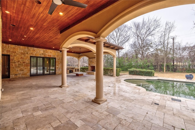 view of swimming pool with ceiling fan, an outdoor fireplace, and a patio