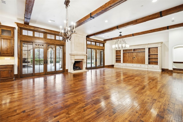 unfurnished living room featuring a fireplace, a chandelier, dark wood-type flooring, beam ceiling, and french doors