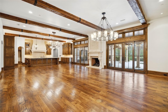 unfurnished living room featuring an inviting chandelier, a premium fireplace, dark hardwood / wood-style flooring, and beamed ceiling