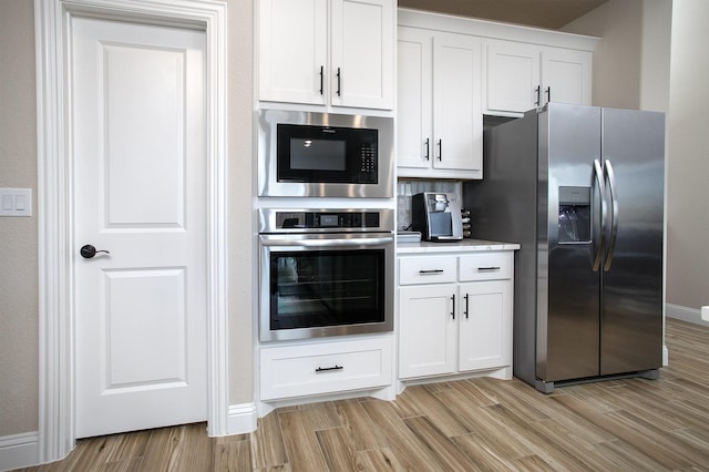 kitchen featuring appliances with stainless steel finishes, white cabinets, and light hardwood / wood-style flooring