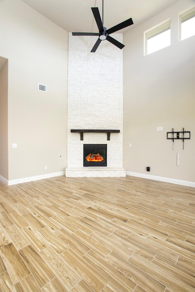 3804 Oakcrest Dr, Rockwall, TX 75032 - unfurnished living room with a high ceiling, ceiling fan, a stone fireplace, and light wood-type flooring
