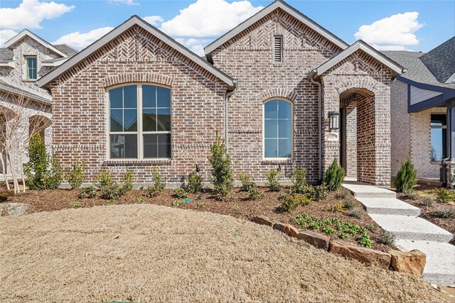 french country home featuring brick siding