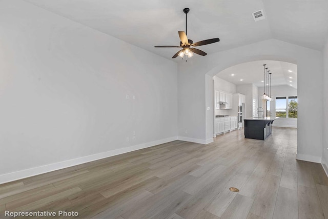 unfurnished living room featuring ceiling fan, sink, vaulted ceiling, and light hardwood / wood-style flooring