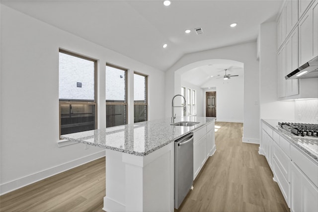 kitchen featuring lofted ceiling, light wood-style flooring, arched walkways, a sink, and stainless steel appliances