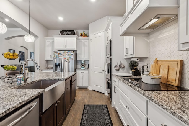 kitchen featuring sink, appliances with stainless steel finishes, white cabinetry, hanging light fixtures, and light stone counters