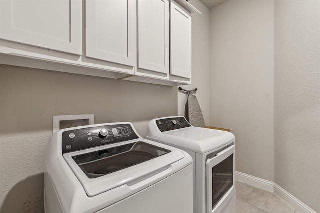 laundry area featuring light tile patterned floors, washer and clothes dryer, and cabinets