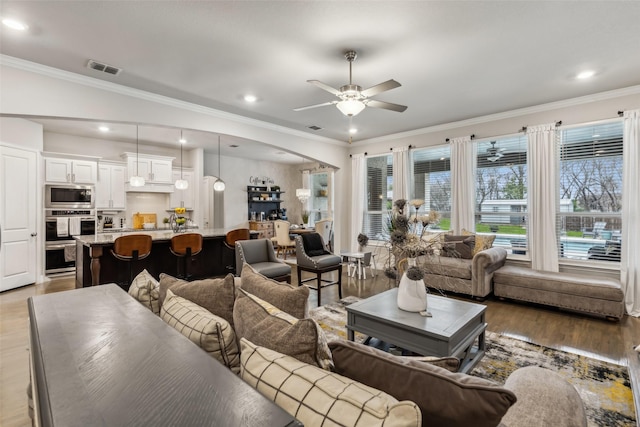 living room with crown molding, ceiling fan, and light hardwood / wood-style flooring