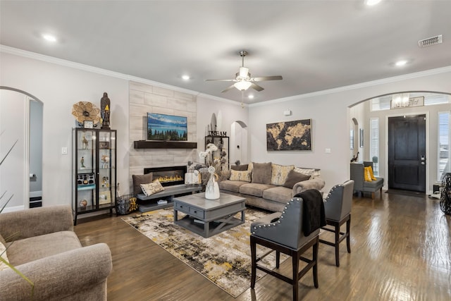 living room featuring crown molding, a fireplace, dark hardwood / wood-style floors, and ceiling fan