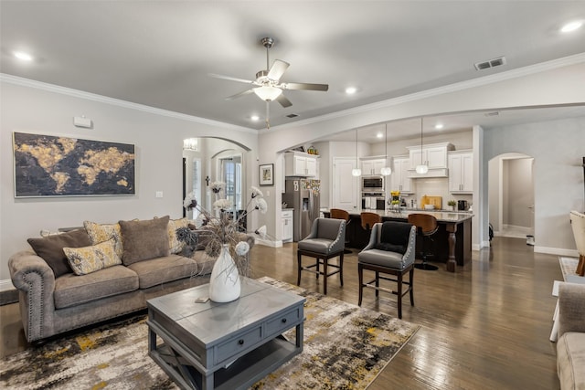 living room with ornamental molding, dark hardwood / wood-style floors, and ceiling fan