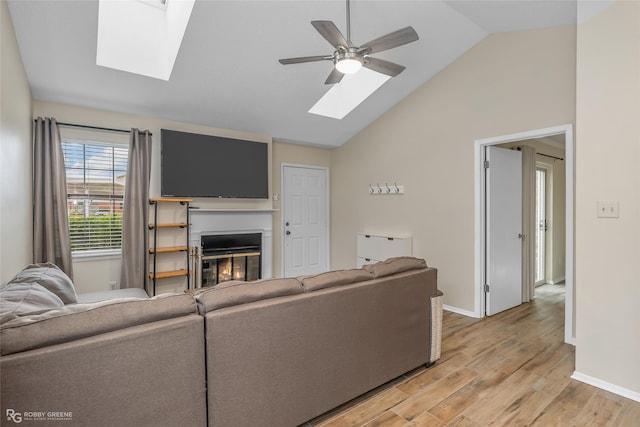 living room featuring light hardwood / wood-style flooring, lofted ceiling with skylight, and ceiling fan