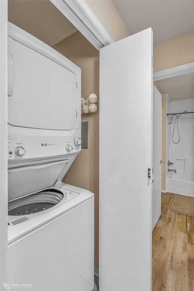 laundry room featuring light wood-type flooring and stacked washing maching and dryer