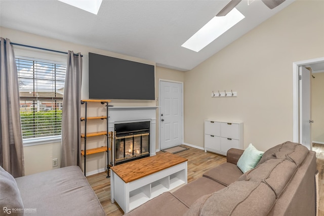 living room with lofted ceiling with skylight and light hardwood / wood-style floors