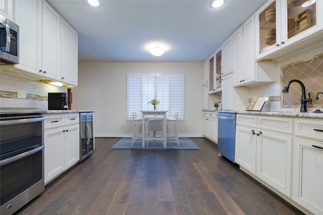 kitchen with light stone counters, white cabinetry, and appliances with stainless steel finishes